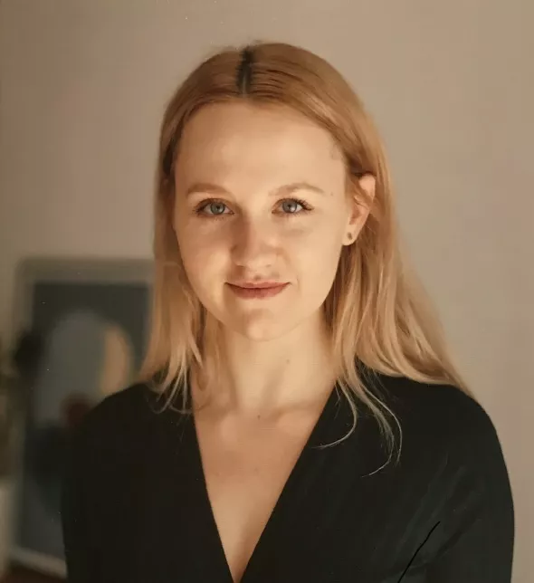 Młoda kobieta z długimi włosami, w czarnej bluzce z dekoltem w serek