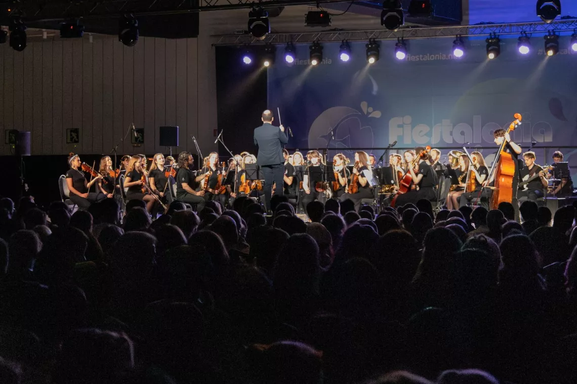 Występ orkiestry na scenie przed liczną publicznością