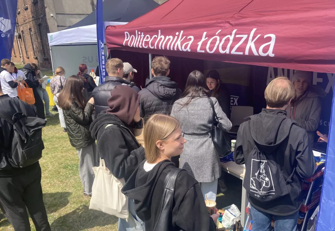 Grupa młodych osób stoi przy namiocie z napisem Politechnika Łódzka