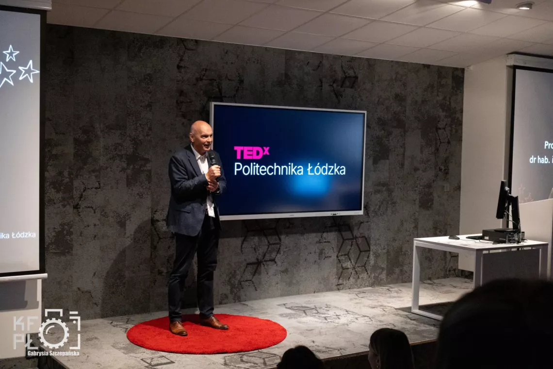 Mężczyzna przemawia do mikrofonu, z tyłu ekran z napisem TEDx Politechnika Łódzka