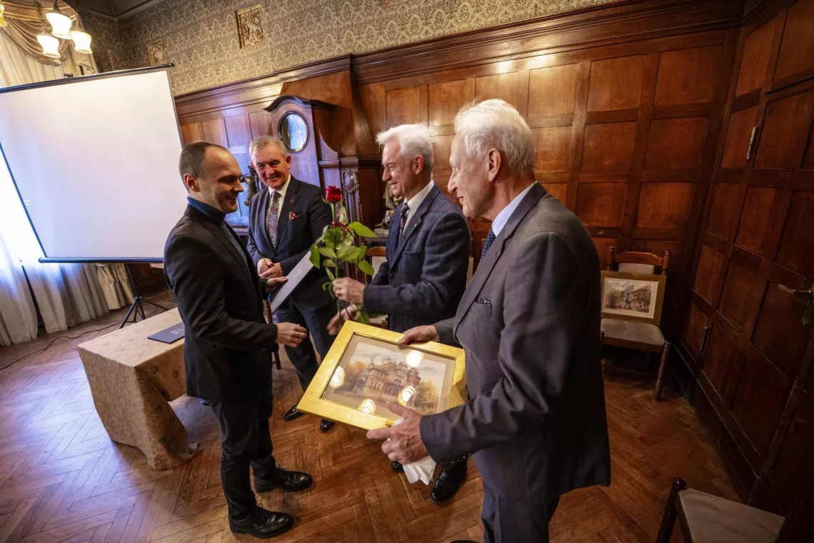 Młody męzczyzna otrzymuje gratulacje od trzrech przredstawicieli śwaita nauki