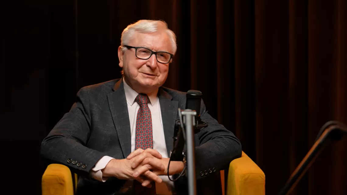 Mężczyzna sidzący w fotelu pzred mikrofonem