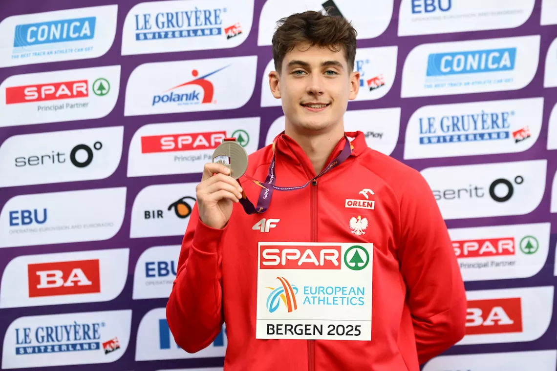 Maksymilian Szwed w reprezentacyjnej bluzie trzyma w ręku srebrny medal