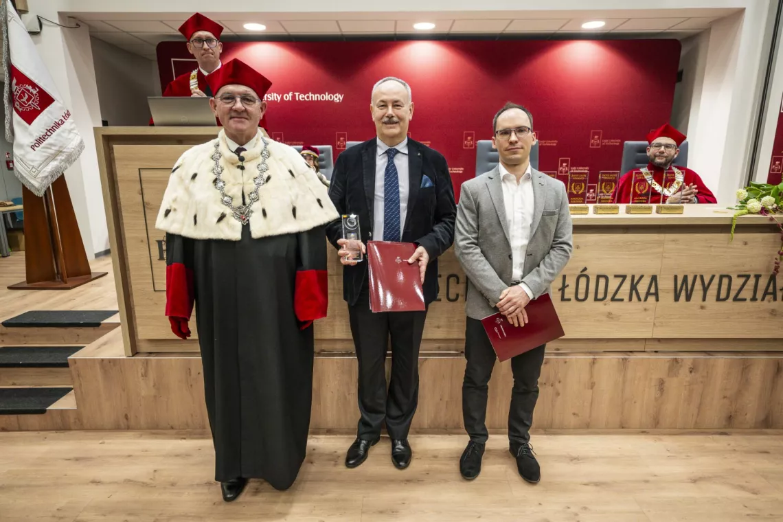 Dwóch mężczyzn, jeden z nich trzyma statuetkę, w towarzystwie rektora