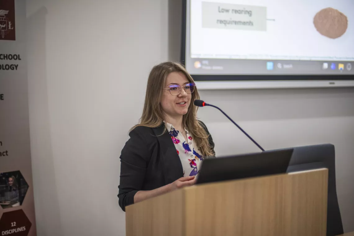 Młoda kobieta występuje, stojąc za mównicą