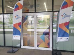 Flagi z napisem Dni Funduszy Europejskich stoją przed drzwiami z napisem PAKT