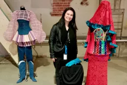 Dr inż. Usmiechnięta kobieta przy futurystycznych projektach sukien wykreowanych przez sudentki 