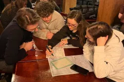 Grupa młodych osób rozwiązująca krzyżówkę