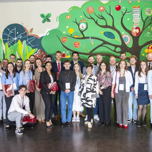 Grupa osób stojących na tle muralu