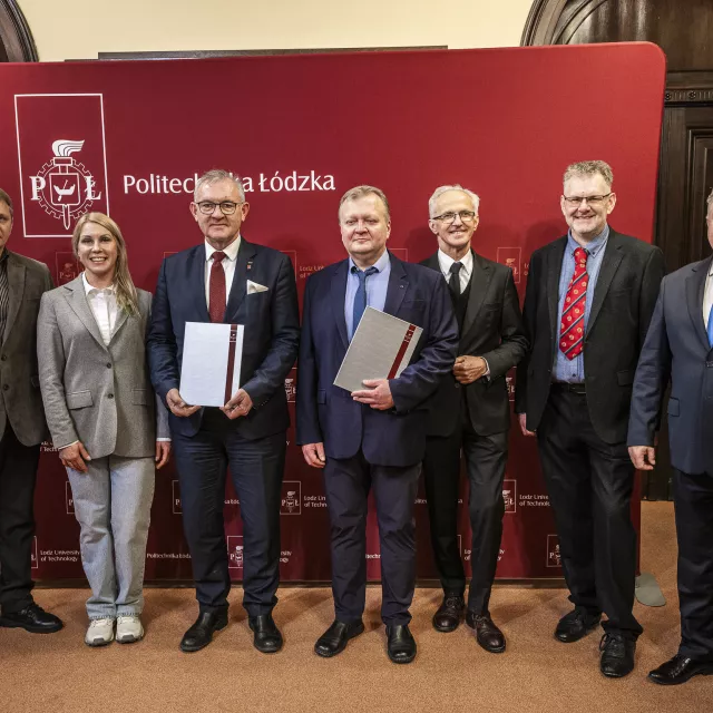 Uczestnicy spotkania z PŁ i USUST na tle ścianki reklamowej PŁ