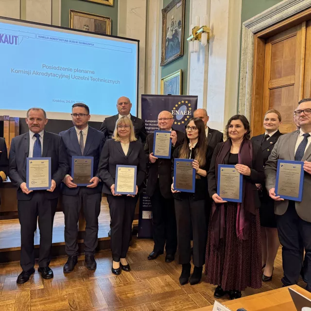 Kilkanaście osób stoi z plakietami w ręku