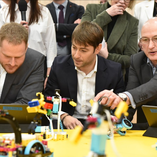Minister Janusz Cieszyński i prezydent Adam Pustelnik programuja roboty pod okiem edukatora