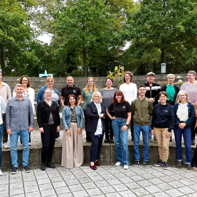 Grupowe zdjęcie wykonane na powietrzu, w tle liściaste drzewa